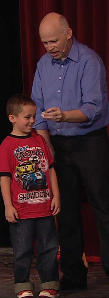 Brad and a child volunteer make magic with money